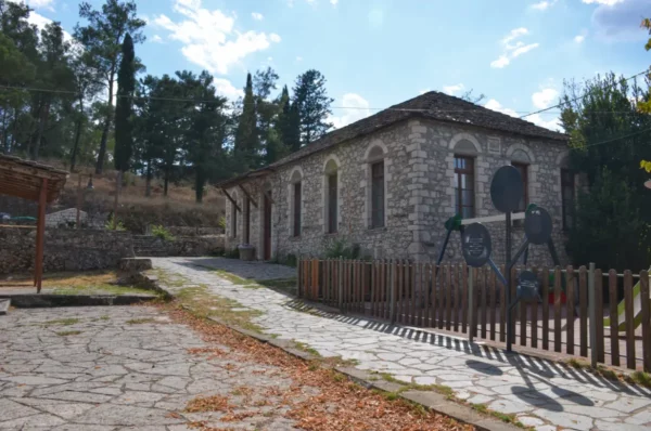 Charming stone building and pathway surrounded by trees on Ioannina Island, Greece, showcasing natural landscape beauty.