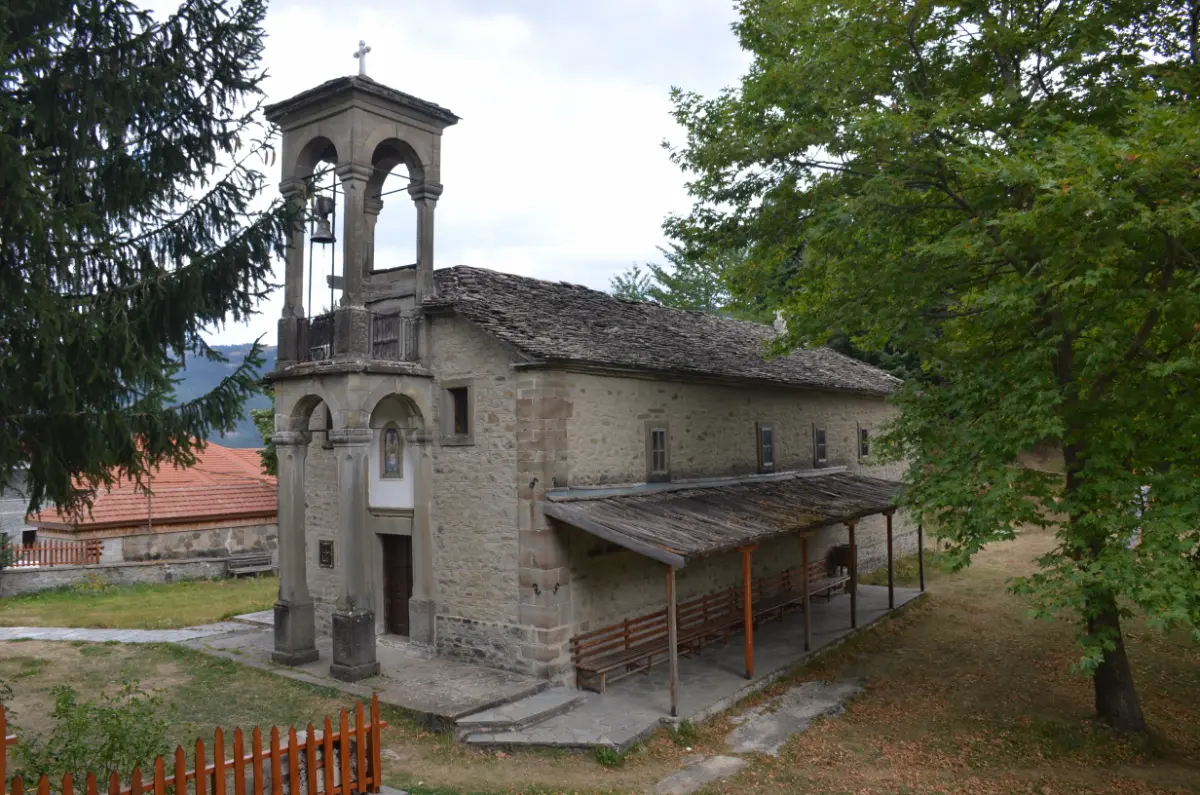 Holy Trinity Church in Metsovo, a stone-built church with a bell tower, surrounded by trees in the Pindus mountains.