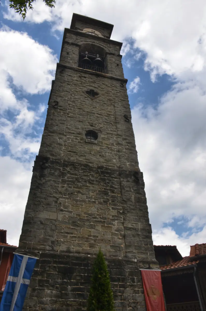 Bell tower of Agia Paraskevi Church in Metsovo — tall stone tower with flags, rising over the central square in the Pindus mountains.