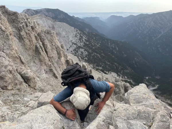 Challenging ascent on rocky terrain at Mount Olympus in Pieria, Greece, with valleys and rugged mountains in the background.