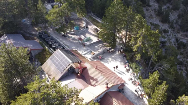 Mount Olympus features a cozy retreat surrounded by lush greenery and visitors enjoying the outdoors in Pieria, Greece.