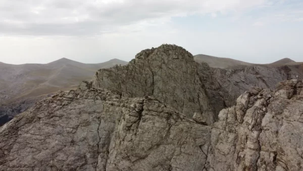 Drone view of Mytikas, the highest peak of Mount Olympus, seen from the east, with rugged limestone ridges and surrounding alpine peaks.