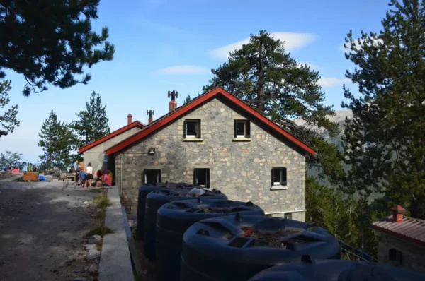 Charming stone building with a red roof surrounded by trees near Mount Olympus, Pieria, Greece, showcasing a serene landscape.