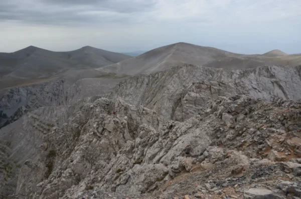 Rugged grey peaks and rocky slopes of Mount Olympus in Pieria, Greece, under a cloudy sky create a dramatic landscape.