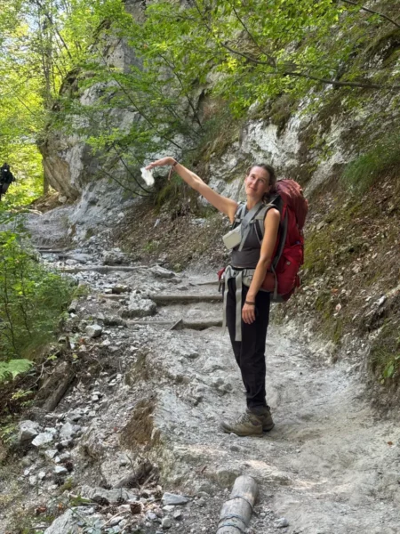 Hiker in a forested path, displaying a map, surrounded by lush greenery on Mount Olympus, Pieria, Greece.