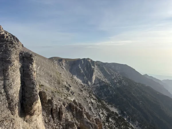 Breathtaking view of rugged cliffs and rocky ridges on Mount Olympus in Pieria, Greece, under a clear blue sky.