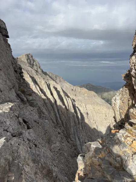 Dramatic cliffs and rugged terrain of Mount Olympus, Pieria, Greece, under a cloudy sky, showcasing nature's raw beauty.