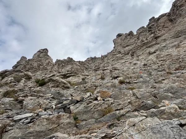 Steep rocky cliffs of Mount Olympus in Pieria, Greece, under a cloudy sky, showcasing rugged textures and natural scenery.