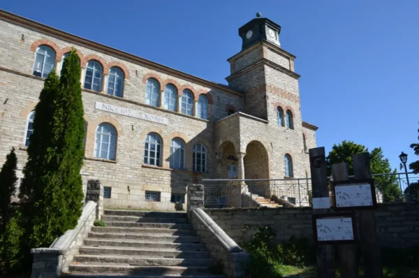 Stone-built Nikeios School in Nymfaio village, Florina, a historic former school building with a central tower and arched entrance, now used as a conference and environmental education center.