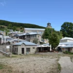 Stone-built houses and the central square of Nymfaio mountain village in Florina, northern Greece, with traditional Macedonian architecture and forested hills in the background.
