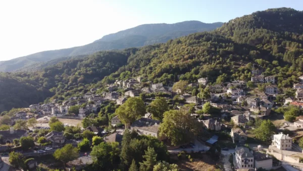 Stunning aerial view of Papigo village in Zagorochoria, showcasing lush greenery and traditional stone houses under a clear sky.
