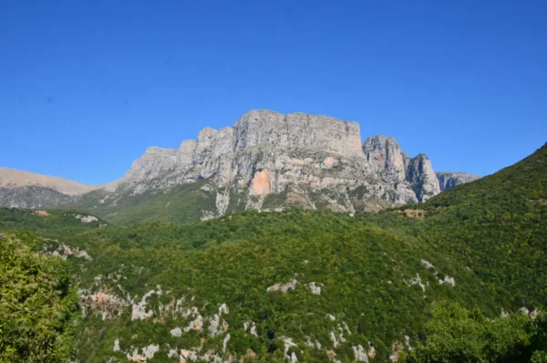 Majestic cliffs rise above lush greenery in Papigo, Zagorochoria, showcasing the natural beauty of Ioannina, Greece.