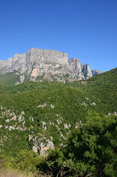 Majestic mountains rise above lush greenery in Papigo, Zagorochoria, showcasing the stunning natural beauty of Ioannina, Greece.