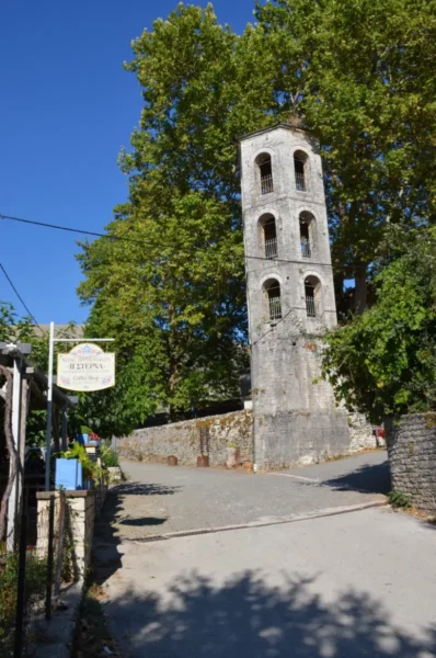 Historic bell tower amidst lush greenery in the charming village of Papigo, Zagorochoria, Ioannina, Greece.