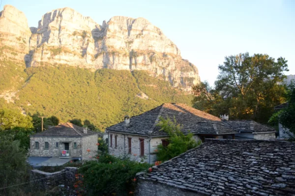Charming stone houses nestled in Papigo, surrounded by lush greenery and the striking mountains of Zagorochoria, Ioannina.