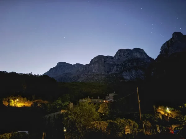 Twilight sky over Papigo, with distant mountains illuminated by soft lights from village homes in Zagorochoria, Ioannina, Greece.