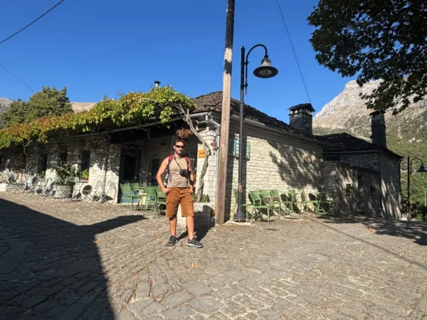 Charming stone house with green vines, outdoor seating, and cobblestone path in Papigo, Zagorochoria, Greece.