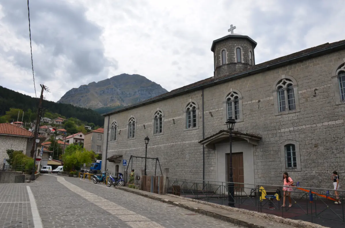the Stone church of Saint Paraskevi in Pramanta, Tzoumerka — long basilica-style building with a dome, set against the mountains.
