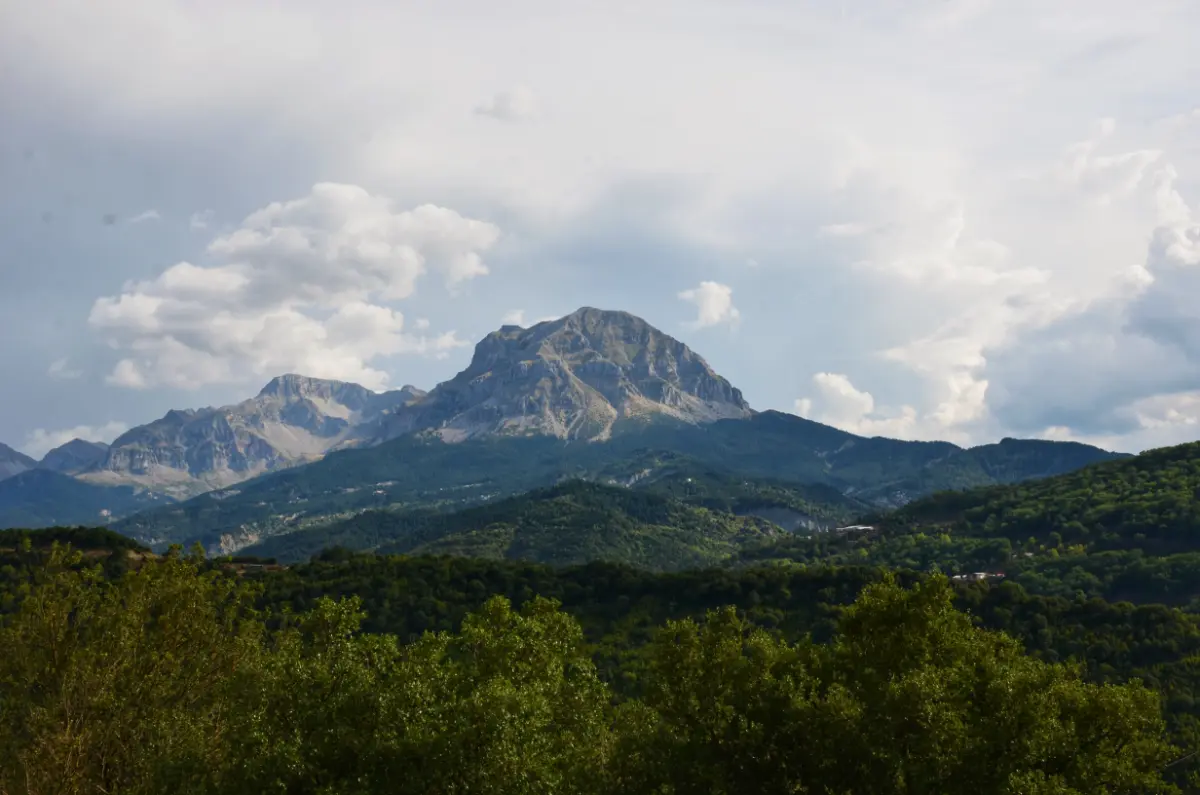 Athamanika (Tzoumerka) Mountains in Epirus, Greece — rugged peaks rising above forested valleys and clouds.