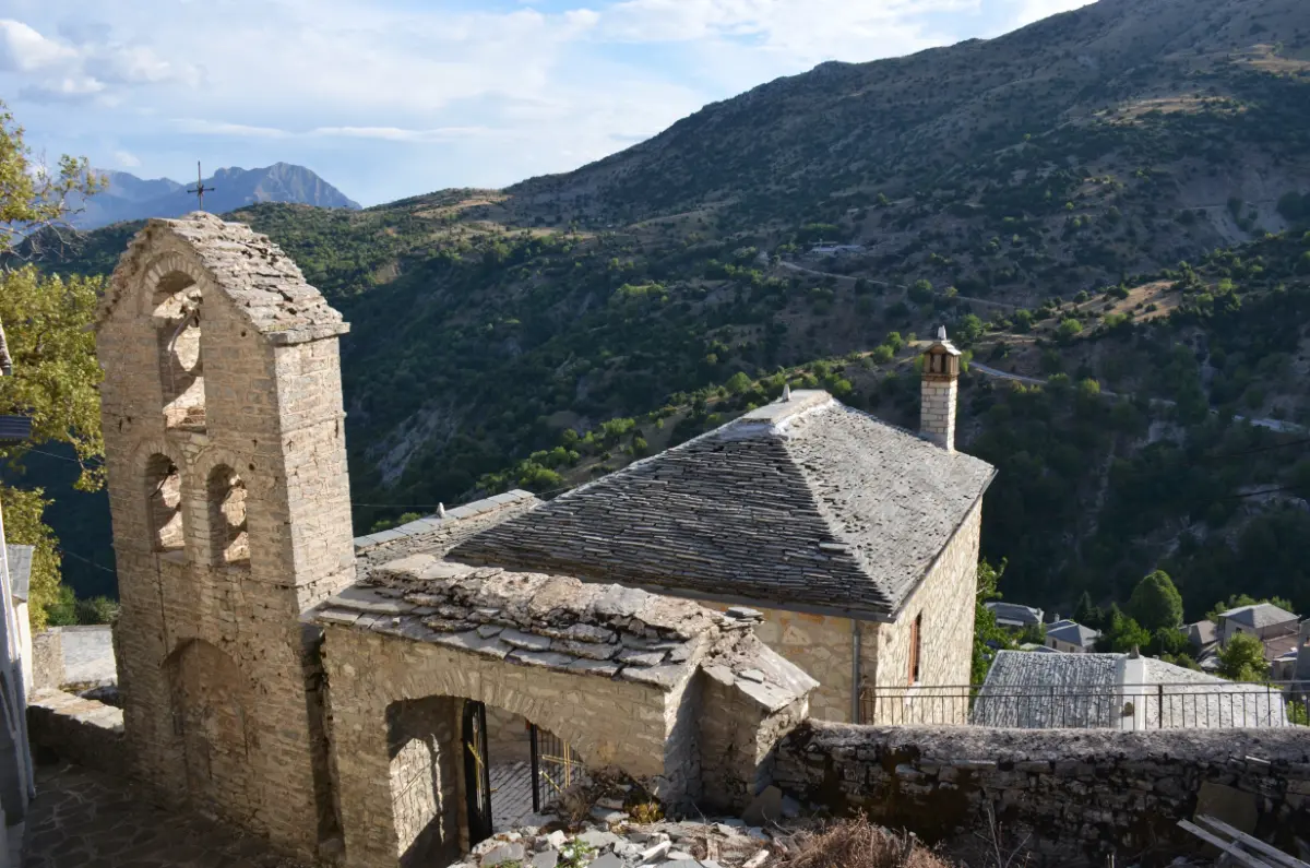 Stone church with a bell tower overlooking the mountains in Syrrako, Tzoumerka.
