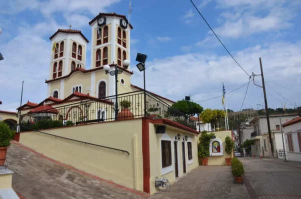 Church of St. John the Theologian in Mantoudi, Evia, Greece, viewed from the entrance with its twin bell towers rising above the surrounding streets.