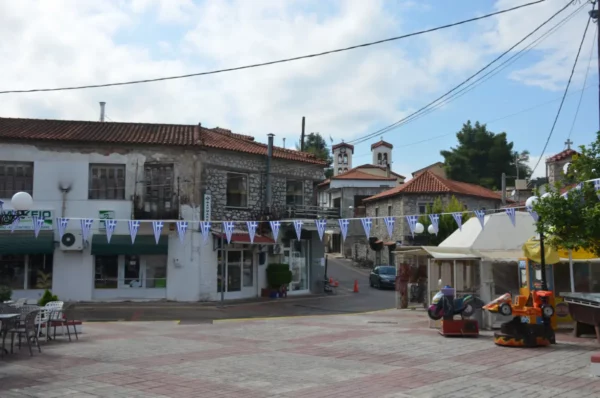 Central square of Mantoudi, Evia, Greece, with cafés, traditional buildings, and the Church of the Holy Trinity in the background.