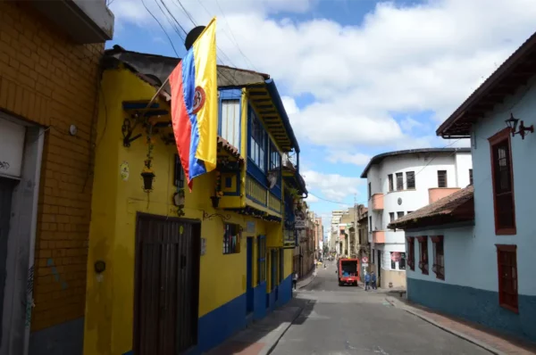 Colonial street in La Candelaria, Bogotá, lined with colorful buildings and a Colombian flag hanging from a wall