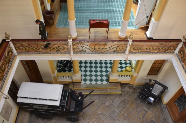 Interior courtyard of the Police Museum of Bogotá viewed from the upper floor, with historic balconies and an armored police vehicle below