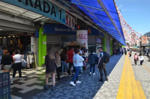Shoppers and pedestrians outside El GranSan Shopping Center in Bogotá beneath colorful awnings and festive decorations