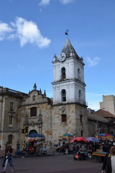 Clock tower of San Francisco Church rising above market stalls along Avenida Jiménez in Bogotá