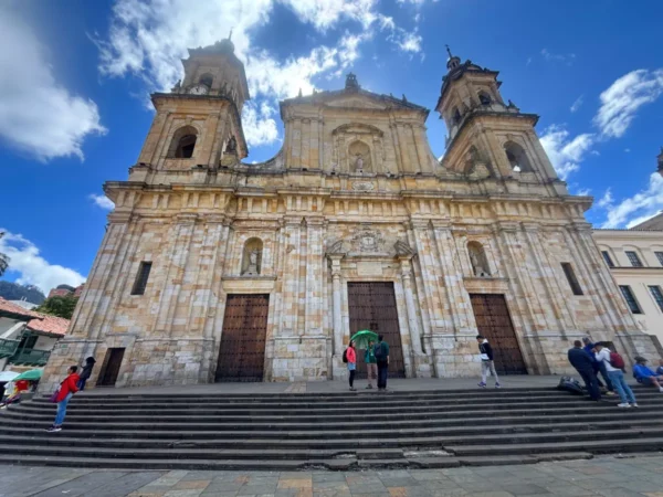 Façade of the Metropolitan Cathedral of Bogotá overlooking Plaza de Bolívar beneath a dramatic blue sky