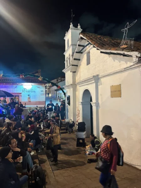 People sitting and socializing outside the Ermita de San Miguel del Príncipe church at Chorro de Quevedo in La Candelaria, Bogotá