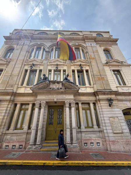 Historic façade of the Police Museum of Bogotá with a large Colombian flag hanging above the entrance in La Candelaria