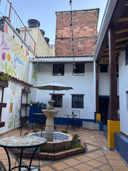 Inner courtyard of Casa de las Plazas guesthouse in La Candelaria, Bogotá, with a central fountain and outdoor seating
