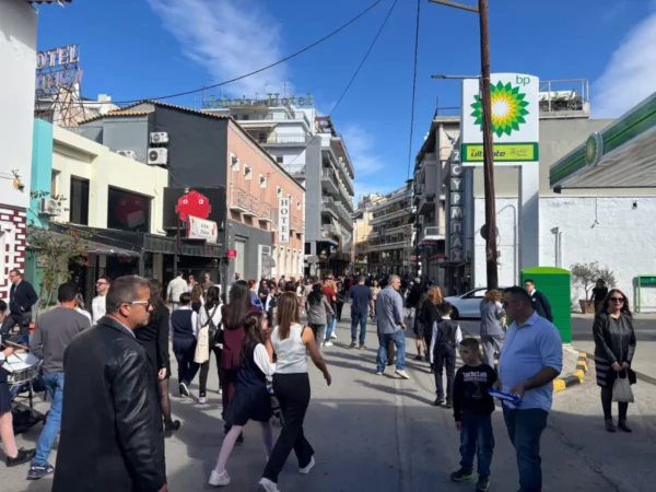 Bustling street scene in Chalkis, Euboea, Greece, with crowds enjoying shops and cafes under a clear blue sky.
