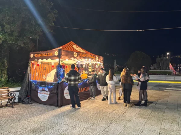 Colorful food stall bustling with people at night in Chalkis, Euboea, Greece, offering local snacks and drinks.