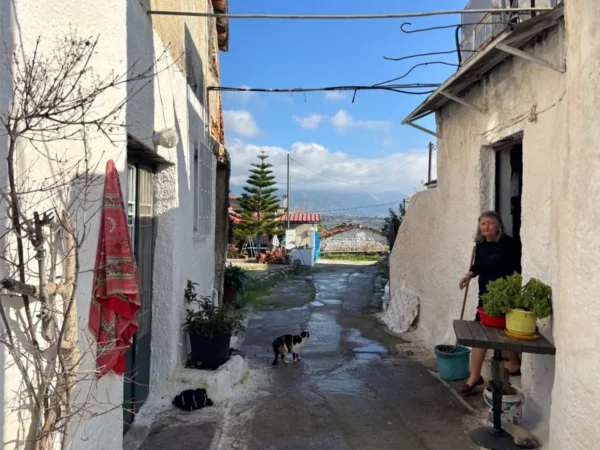 woman exiting house in narrow road in katheni village on evia island