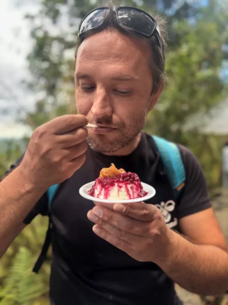 Man eating a serving of cuajada, a traditional Colombian fresh cheese dessert topped with berry syrup, at Monserrate in Bogotá