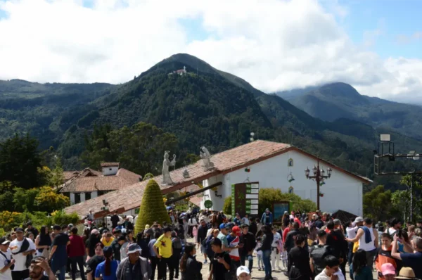 Crowds gathered outside the Basílica del Señor Caído de Monserrate with the forested slopes rising behind