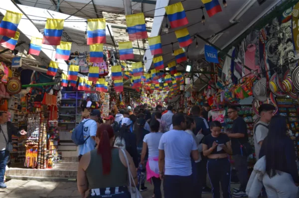 Crowded crafts market at Monserrate in Bogotá, with colorful Colombian flags hanging above souvenir stalls