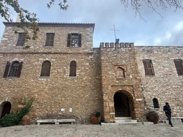 Penteli Monastery features rustic stone walls and arched doorways, surrounded by greenery in Attica, Greece.