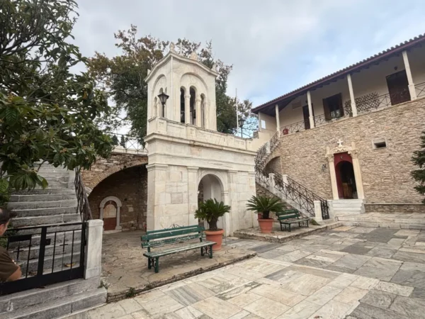Elegant stone steps lead to Penteli Monastery in Attica, Greece, framed by lush greenery and historic architecture.