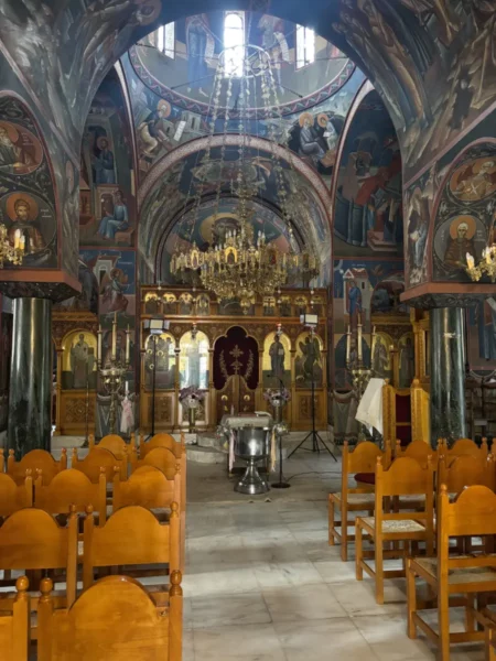 Intricately painted walls and an ornate chandelier illuminate the interior of Penteli Monastery in Attica, Greece.