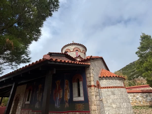Saint Panteleimon Monastery showcases colorful frescoes and traditional stone architecture against a backdrop of Mount Pentelicus, Attica.