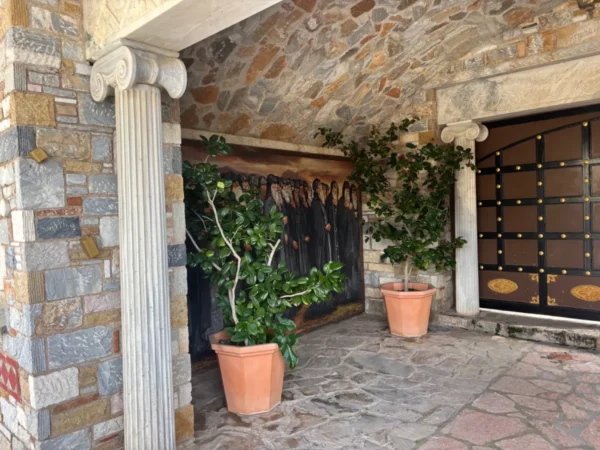 Elegant stone architecture features potted plants and intricate details at Saint Panteleimon Monastery, Mount Pentelicus, Attica, Greece.