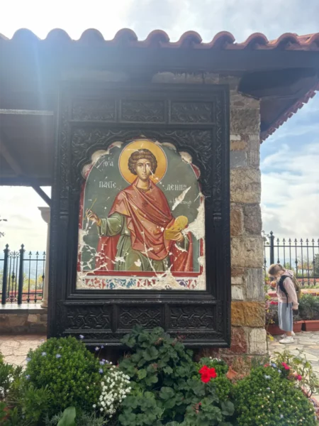 Vibrant fresco of Saint Panteleimon framed by greenery at the monastery on Mount Pentelicus in Attica, Greece.
