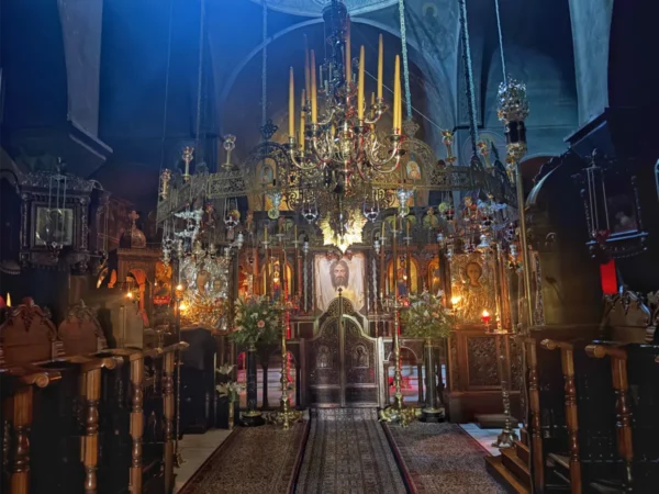 Interior of Saint Panteleimon Monastery features ornate chandeliers, religious icons, and rich colors in a serene atmosphere, Mount Pentelicus, Greece.