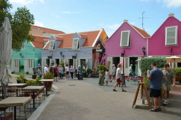 Vibrant pastel buildings line the streets of Kura Hulanda, Willemstad, Curacao, bustling with visitors enjoying the lively atmosphere.