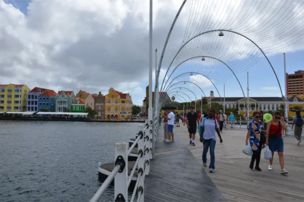 Queen Emma Bridge in Willemstad, Curaçao, with visitors strolling along the wooden walkway.