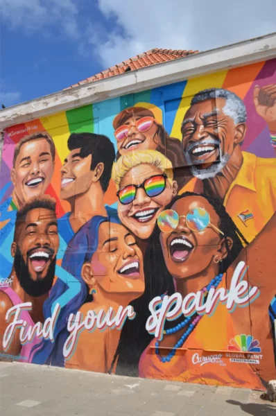 Vibrant mural in Willemstad, Curaçao, featuring diverse faces, colorful backgrounds, and the phrase "Find your spark."